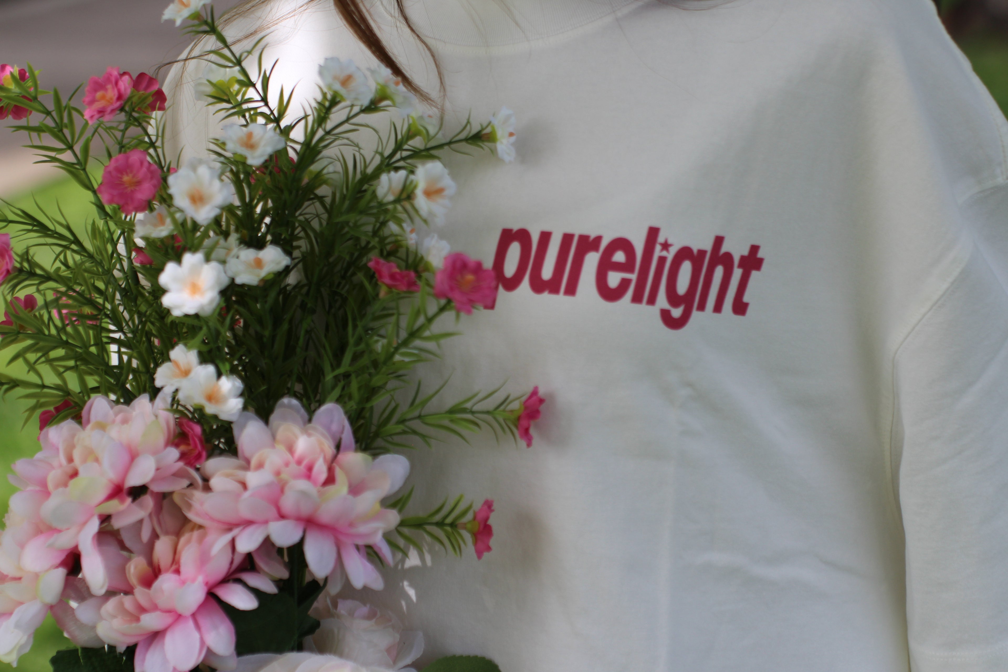 White shirt with 'purelight' text next to a bouquet of flowers