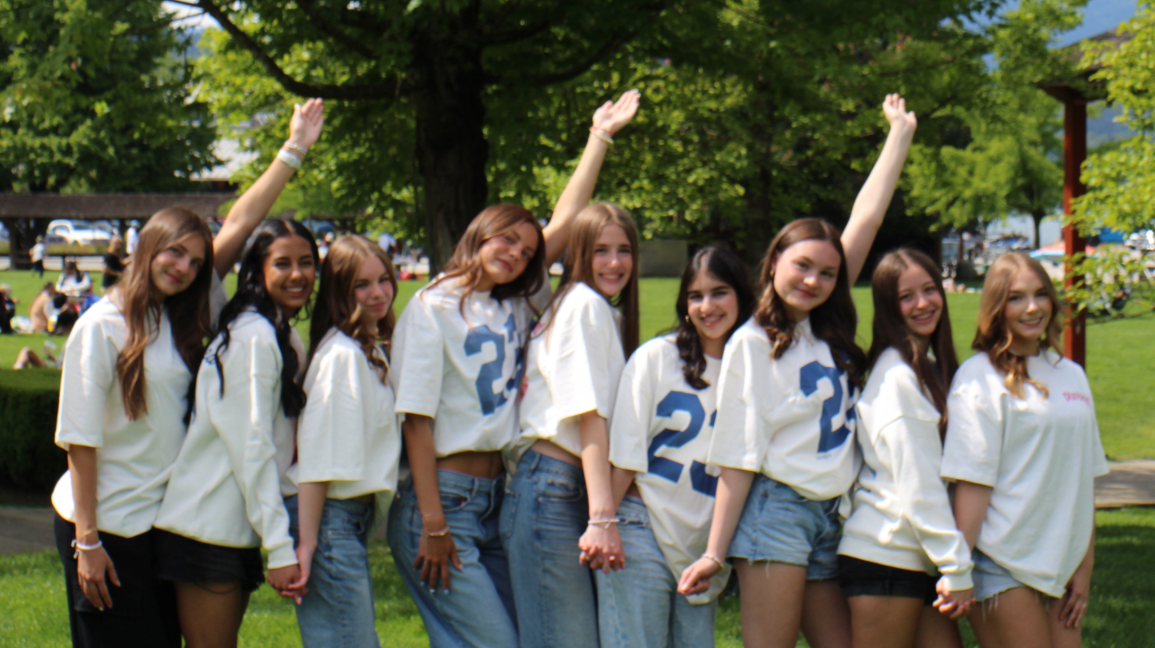 Group of young women posing together outdoors with raised arms