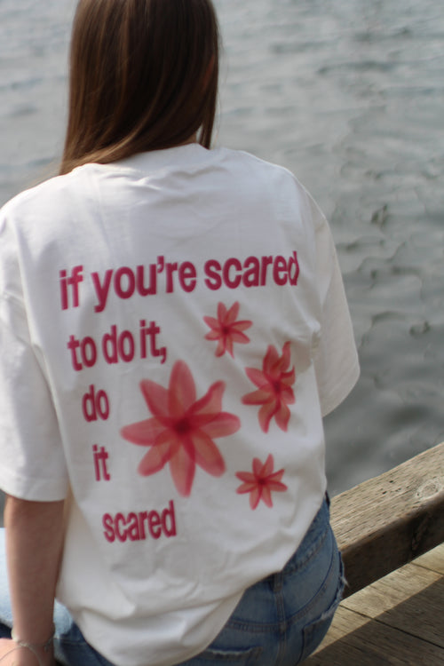 Person wearing a white t-shirt with red floral designs and motivational text.